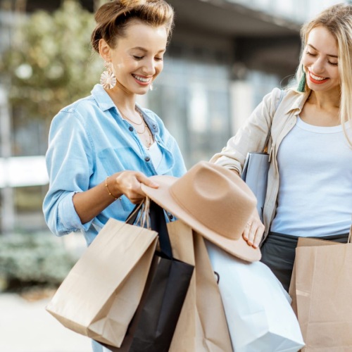two women holding shopping bags and smiling 
