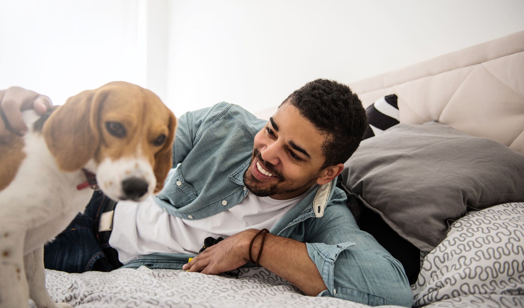 a man on a bed smiling at a dog